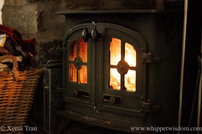 a cast iron wood burning stove with a fire dancing inside
